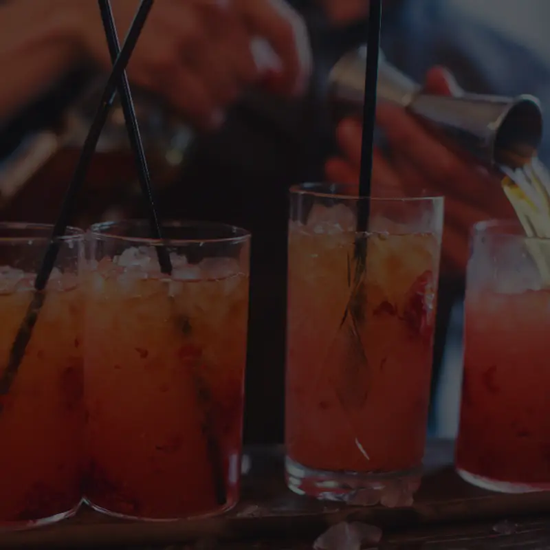Bartender pouring red cocktails into glasses
