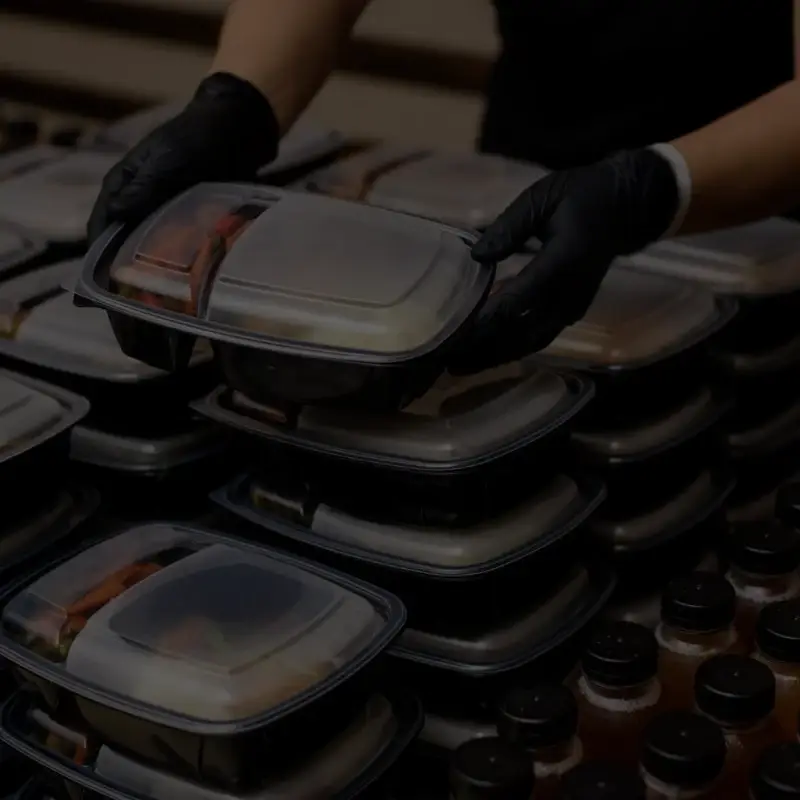 Gloved hands handling stacked meal prep containers
