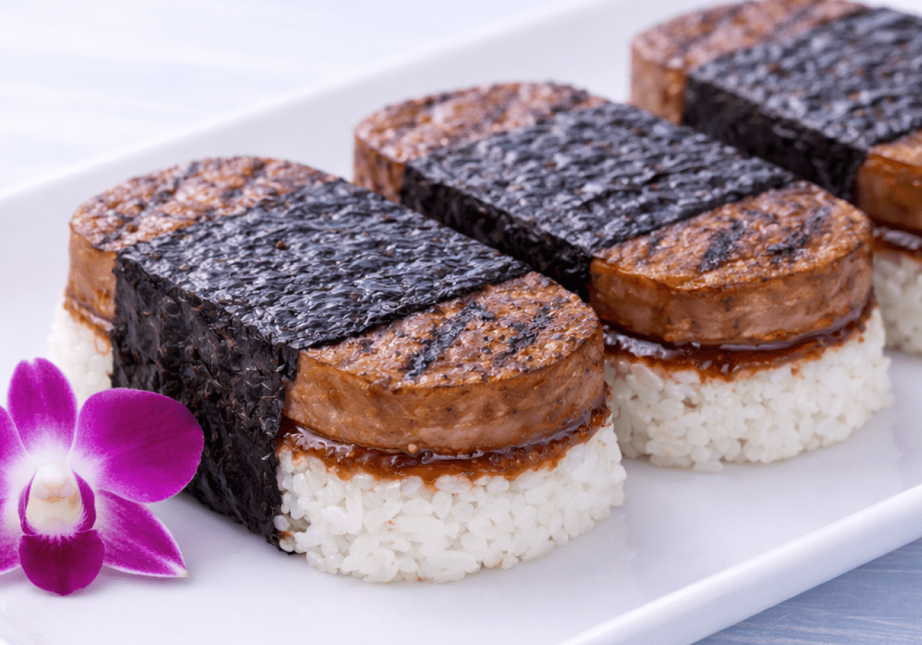 Spam musubi with rice, nori, orchid garnish